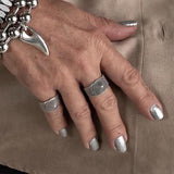 Adjustable silver plated ring with a dark ethnic cone and dot design, worn on the thumb amid other rings.
