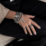 Adjustable silver plated ring with dark ethnic cone and dots design, worn on pinky finger alongside chunky silver bracelets.