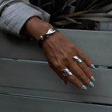 Adjustable silver-plated statement ring set worn on a hand, featuring chunky designs with a shiny finish.