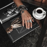 Adjustable silver-plated chunky rings worn on a hand, styled with bold silver accessories, resting on a magazine.
