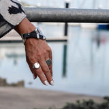 Bold snake chain bracelet featuring woven leather band in black, complemented by silver metal accents and adjustable fit.