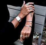 Chunky minimalist metallic cuffs featuring a wide flat cuff and open double band cuff, both in shiny rhodium-plated brass.