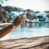 Chunky minimalist metallic cuffs, a wide flat cuff and an open double band bracelet worn on a hand against a scenic backdrop.