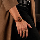 Hammered gold-plated metal ring with a circular geometric design, worn on a thumb, showcasing its adjustable fit.