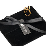 Hammered gold-plated adjustable ring featuring a circular geometric design, resting on a black suede pouch with ribbon.