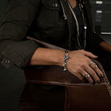 Chic silver stainless steel bracelet featuring Swarovski crystal charm and unique T-bar closure, worn with a stylish outfit.