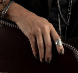 Adjustable boho ring with floral engraving, worn on the index finger; model's hand rests on a brown bag.