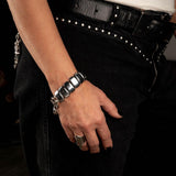 Chunky hematite gemstone cuff bracelet with a gunmetal heart buckle, worn on a wrist, styled with black jeans.