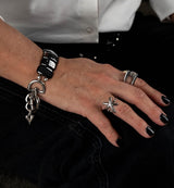 Chunky hematite gemstone cuff bracelet with a bold gunmetal heart buckle, worn on a model's wrist with stylish rings.