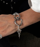 Chunky adjustable cuff bracelet featuring a gunmetal heart buckle with a shiny silver finish, worn on a wrist.