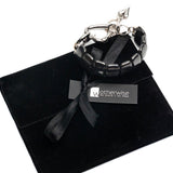 Chunky black hematite gemstone cuff bracelet with a shiny gunmetal heart buckle, displayed on a black suede pouch.