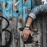 Set of three adjustable silver-tone punk rings displayed on a hand, accessorized with a leather bracelet, against a rustic wooden backdrop.