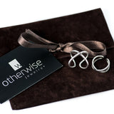 Three silver-tone punk rings are displayed on a dark brown suede pouch, with a ribbon tied neatly. Each ring features a unique design.