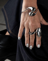 Elegant cuff bracelet in shiny stainless steel with large drops, worn over a sleeve on a model's wrist.