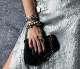 Shell pearl bracelet with thick silver-plated brass chain worn stacked with other metallic bracelets on a wrist.