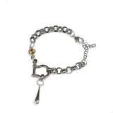 Chunky stainless-steel rolo chain bracelet with a shackle and teardrop pendant. Features a tea-colored Austrian crystal.