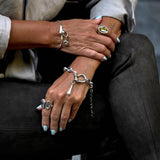 Chunky rolo chain bracelet features a shackle and teardrop pendant with a blue Austrian crystal. Worn on the wrist, adjustable fit.