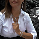 Chunky sterling silver-plated hoop earrings with a teardrop charm, worn by a model in a white shirt.