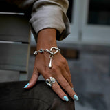 Chunky stainless-steel rolo chain bracelet featuring a U-bolt shackle and teardrop pendant, with a gray Austrian crystal.
