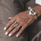 Close-up of a hand wearing silver rings and a bracelet on a brown background