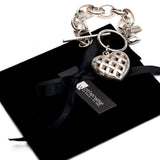 Textured heart charm bracelet on a black suede pouch, featuring an antique-plated chain and woven heart pendant.
