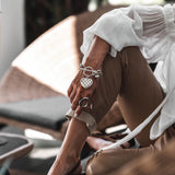 Textured heart charm bracelet featuring a detailed heart pendant on an antique-plated chain, worn with a stylish outfit.