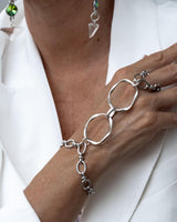 Handmade stainless steel chain hand harness connecting a ring and bracelet, featuring a bold, edgy design.