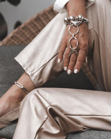 Handmade stainless steel chain hand harness features a layered ring and bracelet connected by a fluid chain, shown on a model's hand.