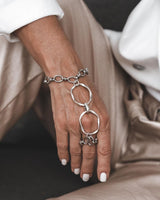 Handmade stainless steel chain hand harness featuring a ring connected to a wrist bracelet, showcased elegantly on a model's hand.