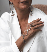 Handmade stainless steel chain hand harness featuring a sleek ring connected to a wrist bracelet. Elegant design rests on the wrist.