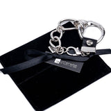 Chunky silver-plated bracelet featuring a large hoop, horse bit buckle, and black leather accents, presented on a suede pouch.