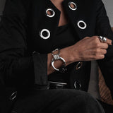 Chunky silver-plated bracelet with a large hoop and leather, worn on a model's wrist, styled with a black jacket.