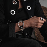 Chunky silver-plated cuff bracelet with black leather, featuring a large hoop and horse bit design, worn on a model's wrist.