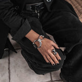 Chunky silver large hoop bracelet with a horse bit design, paired with a sleek black leather accent, worn on a wrist.