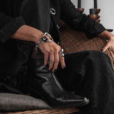 Chunky silver large hoop bracelet with a horse bit buckle, paired with black leather, worn on a model's wrist.