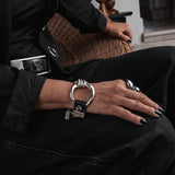 Chunky silver-plated cuff bracelet with a large hoop and black leather, styled with a distinctive horse bit buckle.