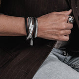 Layered black leather and silver snake chain wraparound bracelet, featuring a malleable bangle and adjustable closures.