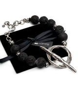 Chunky black lava stone choker necklace with oversized silver T-clasp toggle, presented on a black velvet pouch.