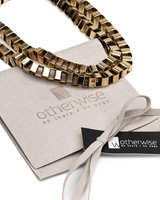Layered gold and silver chokers featuring textured steel box chains, presented with a sleek suede pouch.