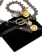 Necklace with charms on a black velvet pillow, brand tag visible
