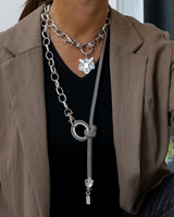 Chunky antique silver choker with a tiger head pendant layered with a long steel chain necklace featuring a knot detail.