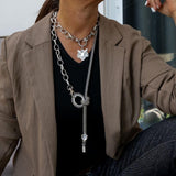 Chunky antique silver choker with a tiger head pendant layered with a long steel chain necklace featuring a knot detail.