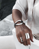 Black leather and irregular silver metal cuff bracelet worn on a wrist, showcasing an edgy rock style look.