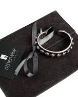 Silver hoop earring with decorative beads on a black box with 'otherwise jewelry' card.