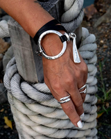 Bold wrap leather and metal cuff bracelet featuring multi-strand leather and sculpted silver-plated hardware, worn on a wrist.