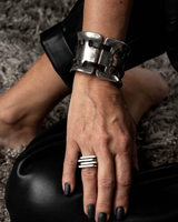 Close-up of a hand wearing multiple silver rings with a textured background