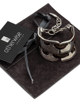 Silver bracelet on a dark fabric with 'otherwise jewelry' card