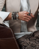 Person wearing multiple bracelets and rings on a blurred background