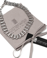 Silver necklace on a gray card with 'otherwise' branding