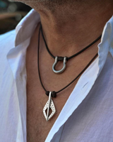 Close-up of a person wearing two necklaces with unique pendants on a blurred background.